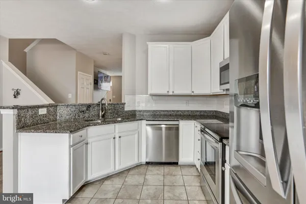 a kitchen with white cabinets appliances and a sink
