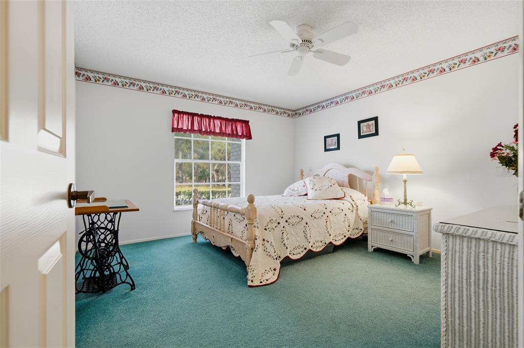 7354 Woodhollow Road Spring Hill, FL 34606 - Photo 28 of 47 a spacious bedroom with a bed and a chandelier