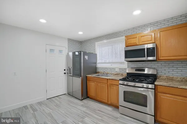 a kitchen with stainless steel appliances a stove a microwave and a hard wood floor