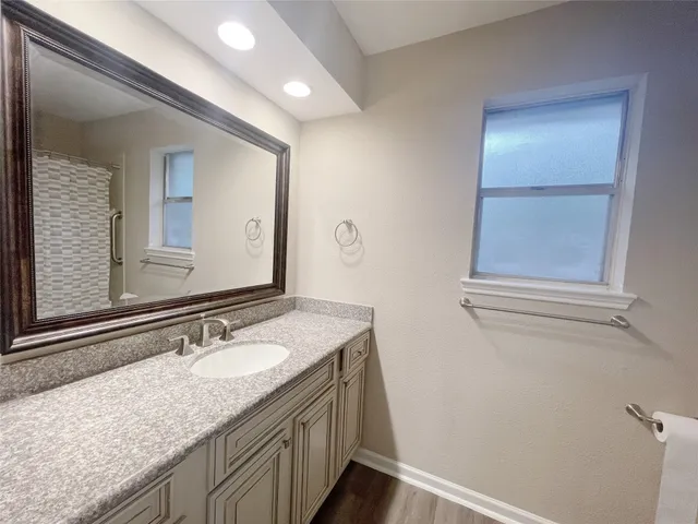 a bathroom with a granite countertop sink and a mirror