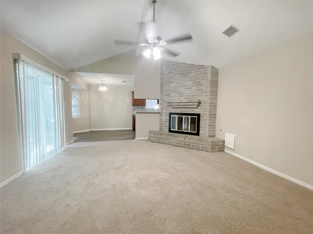 a view of a livingroom with a fireplace a ceiling fan and window