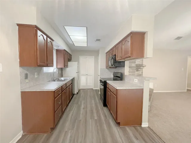 a kitchen with sink a stove top oven and wooden cabinets