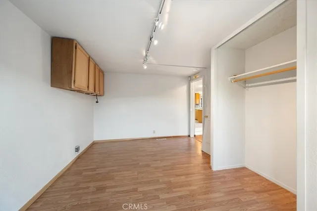 a view of empty room with wooden floor and fan