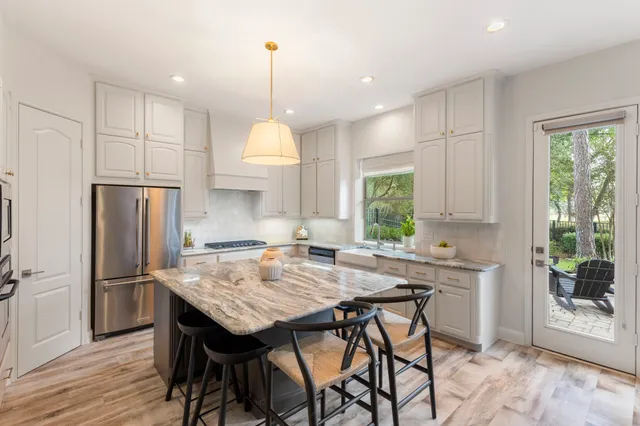 a kitchen with granite countertop a table chairs stainless steel appliances and wooden floor