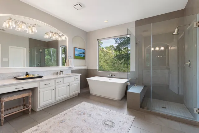 a spacious bathroom with a double vanity sink a large mirror and a bathtub