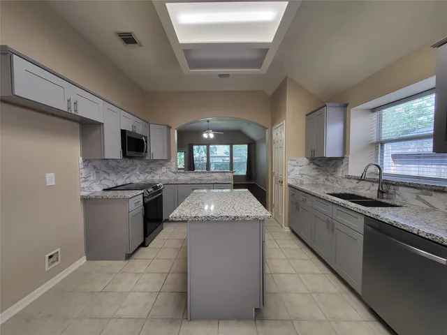 a large kitchen with granite countertop a sink and cabinets