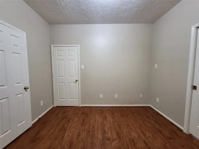 a view of an empty room with wooden floor and closet