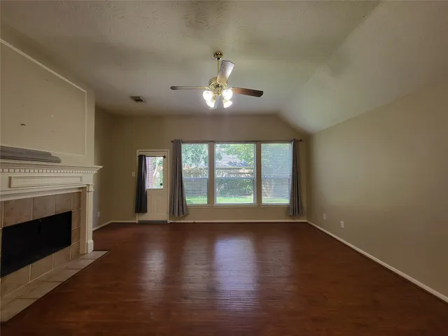 a view of an empty room with wooden floor fireplace and a window
