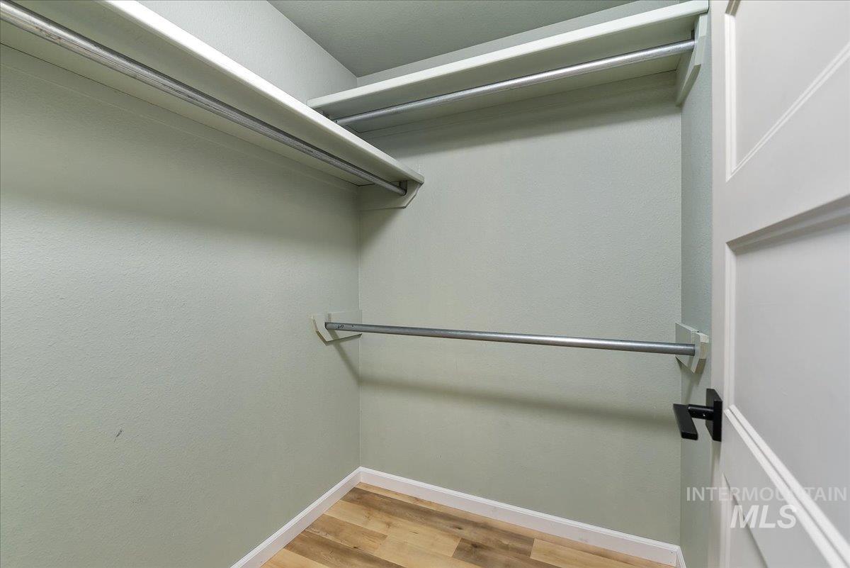 9215 West Preece Street Boise, ID 83704 - Photo 16 of 22 Interior closet featuring neutral wall color, two levels of hanging rods, an additional lower hanging rod, wood-finish flooring, and white baseboards