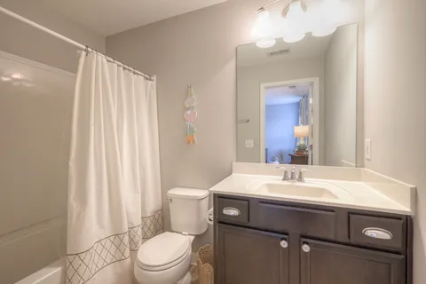 a bathroom with a sink a toilet a mirror and shower curtain