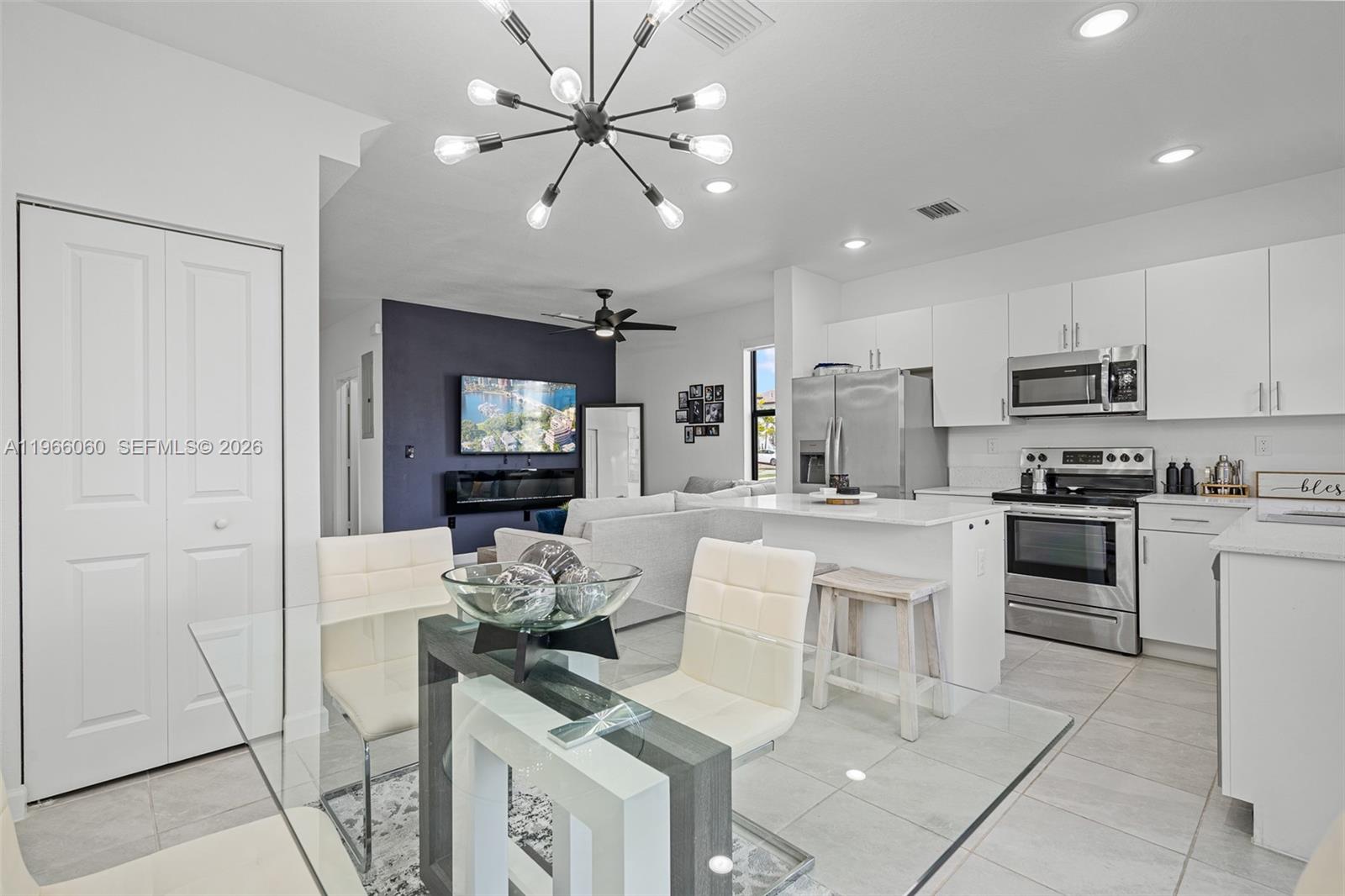 9941 Southwest 231st Lane, Unit 9941 Miami, FL 33190 - Photo 14 of 29 a kitchen with stainless steel appliances kitchen island granite countertop a refrigerator a stove a microwave oven a sink with island and chairs