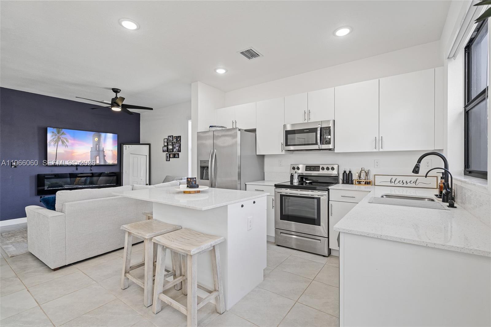 9941 Southwest 231st Lane, Unit 9941 Miami, FL 33190 - Photo 10 of 29 a kitchen with microwave a stove and white cabinets