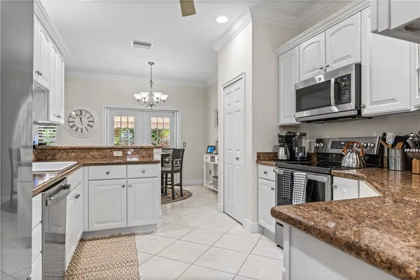 a kitchen with stainless steel appliances granite countertop a stove top oven a sink dishwasher and a refrigerator with wooden cabinets