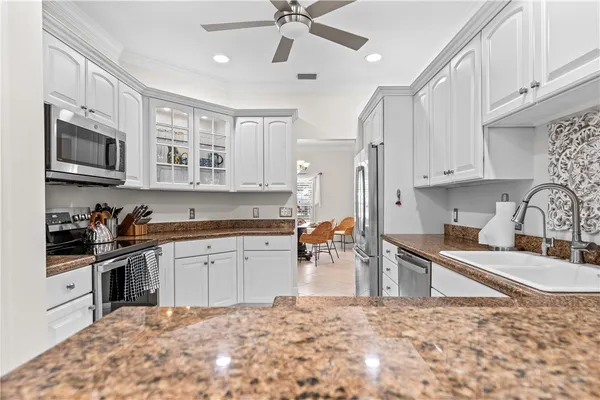 a kitchen with stainless steel appliances granite countertop a sink stove oven and white cabinets