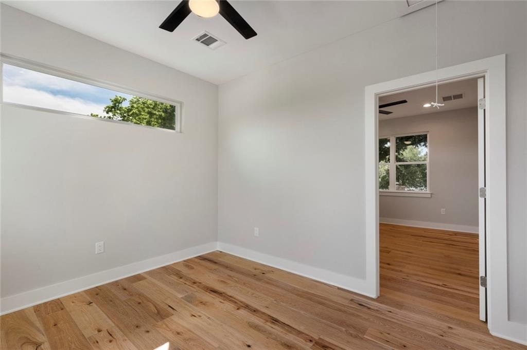 1107 Stobaugh Street, Unit 1 Austin, TX 78757 - Photo 19 of 27 an empty room with wooden floor chandelier fan and windows