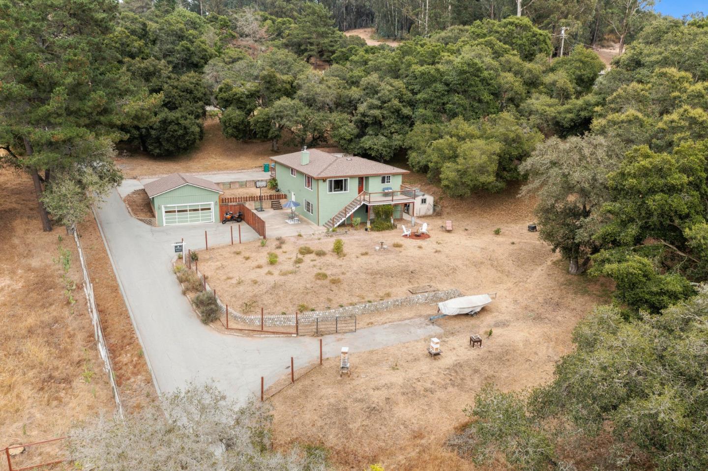 an aerial view of a house with yard and trees in the background