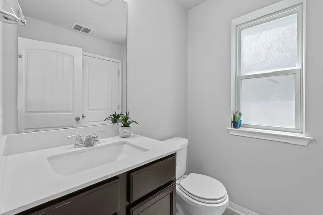 a bathroom with a sink vanity mirror and toilet