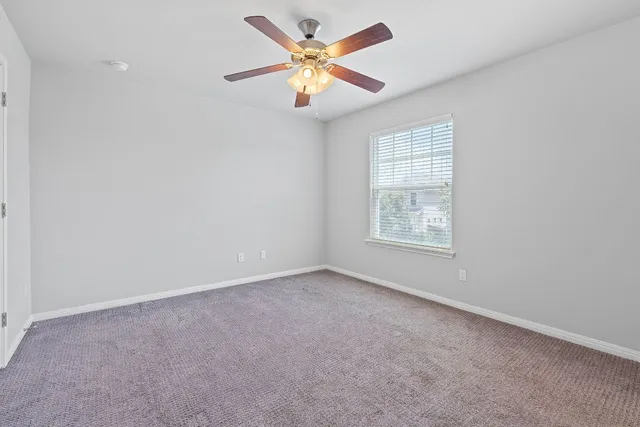 an empty room with windows and ceiling fan