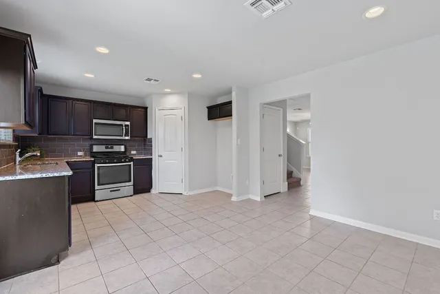 a kitchen with stainless steel appliances granite countertop a refrigerator and a stove top oven
