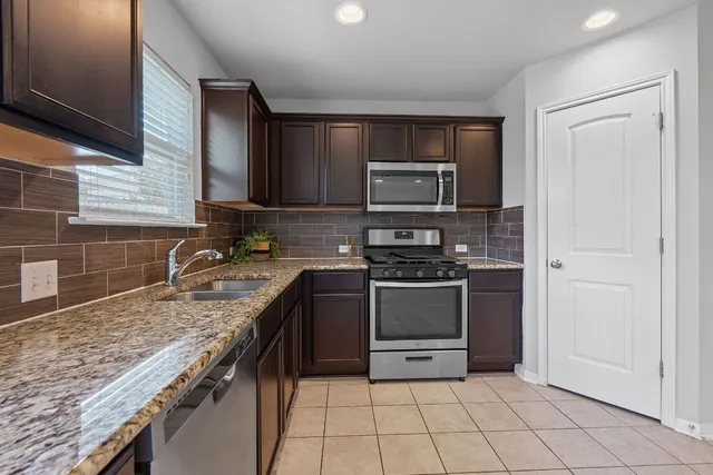 a kitchen with stainless steel appliances granite countertop a stove microwave and sink