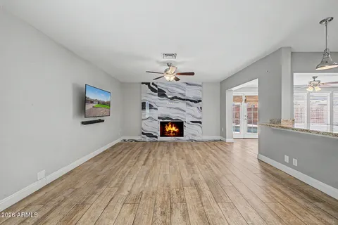 a view of an empty room with wooden floor fireplace and a window