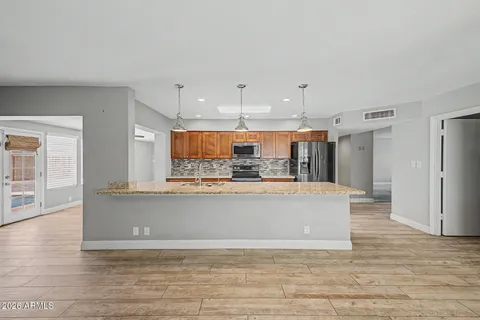 a view of a kitchen with kitchen island stainless steel appliances wooden floor and view living room