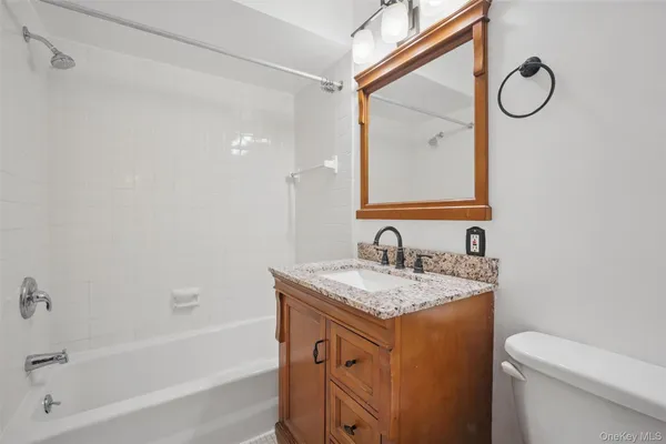 a bathroom with a granite countertop sink mirror vanity and toilet
