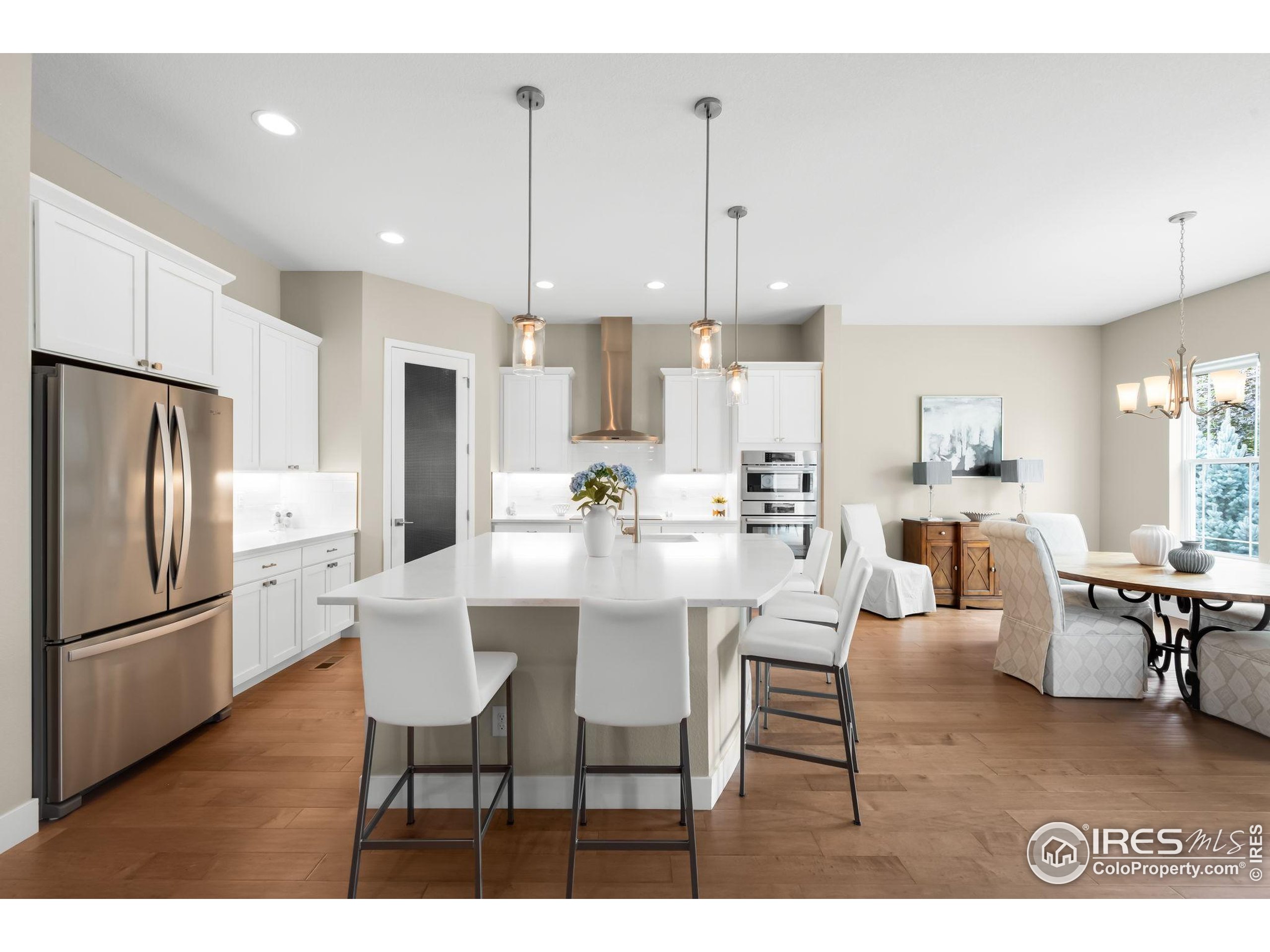 5799 Howell Street Golden, CO 80403 - Photo 9 of 50 a kitchen with stainless steel appliances kitchen island granite countertop a dining table chairs and a refrigerator