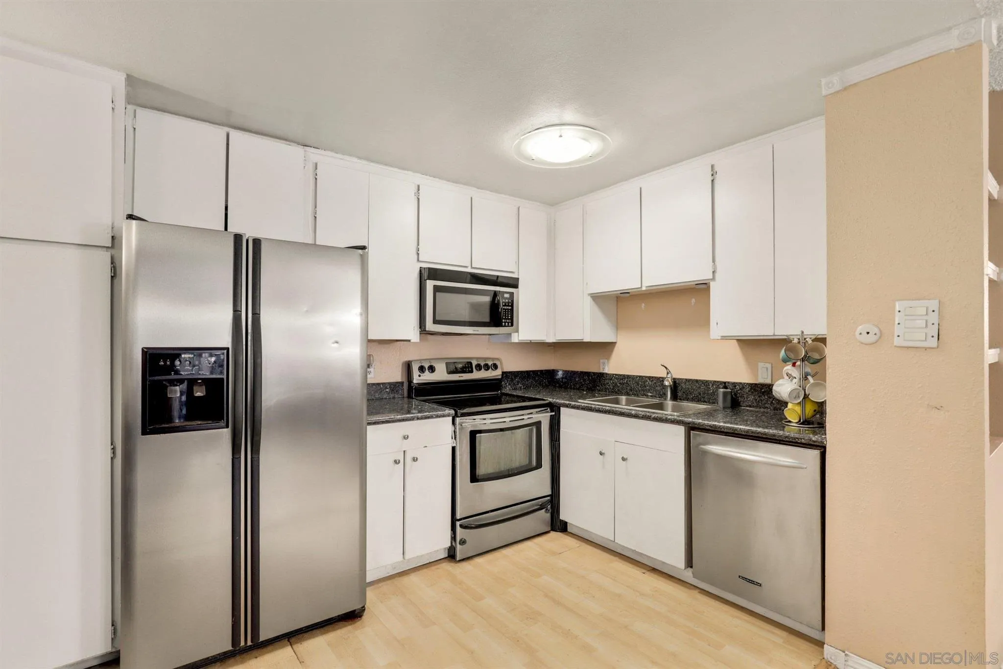 6370 Rancho Mission Road, Unit 920 San Diego, CA 92108 - Photo 5 of 22 a kitchen with stainless steel appliances granite countertop a refrigerator a stove a sink and white cabinets