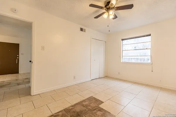 a view of an empty room and window and chandelier fan