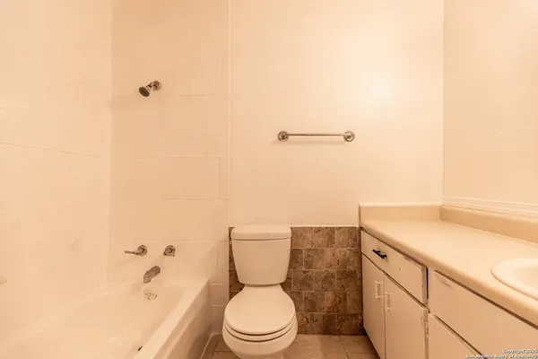 a bathroom with a granite countertop toilet and a sink
