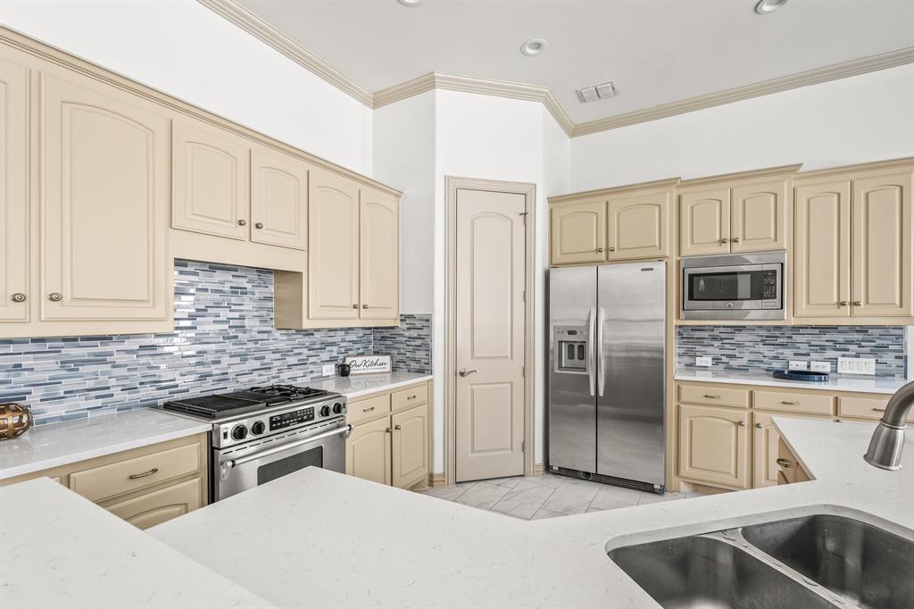 6393 Burnham Street Frisco, TX 75034 - Photo 16 of 30 a kitchen with stainless steel appliances granite countertop a sink stove and refrigerator