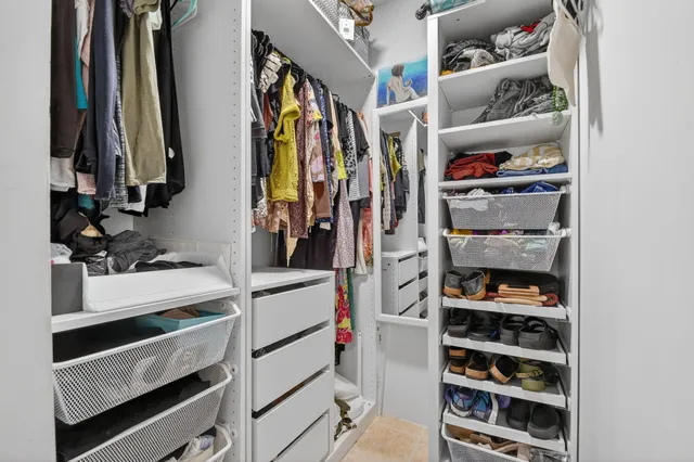 a view of walk in closet with clothes and shoes