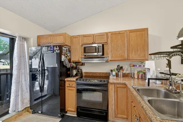 a kitchen with stainless steel appliances granite countertop a sink a stove and a refrigerator