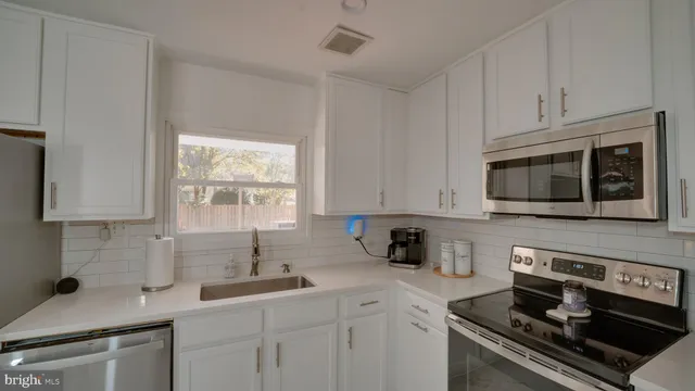 a kitchen with stainless steel appliances granite countertop white cabinets a stove a sink and dishwasher