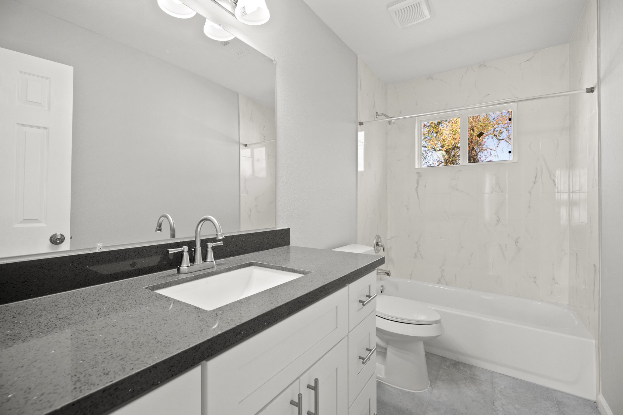 5123 Ridgeway Drive Houston, TX 77033 - Photo 15 of 21 Secondary Bathroom with tile floors, granite countertops and backsplash, a large mirror, and a shower/tub combo.