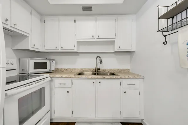 a kitchen with granite countertop white cabinets and white appliances