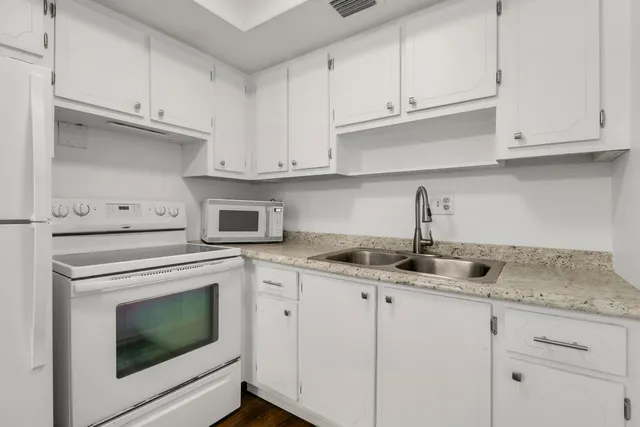 a kitchen with granite countertop white cabinets and white appliances
