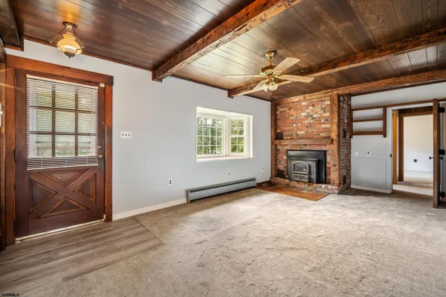 an empty room with windows fireplace and flat screen tv