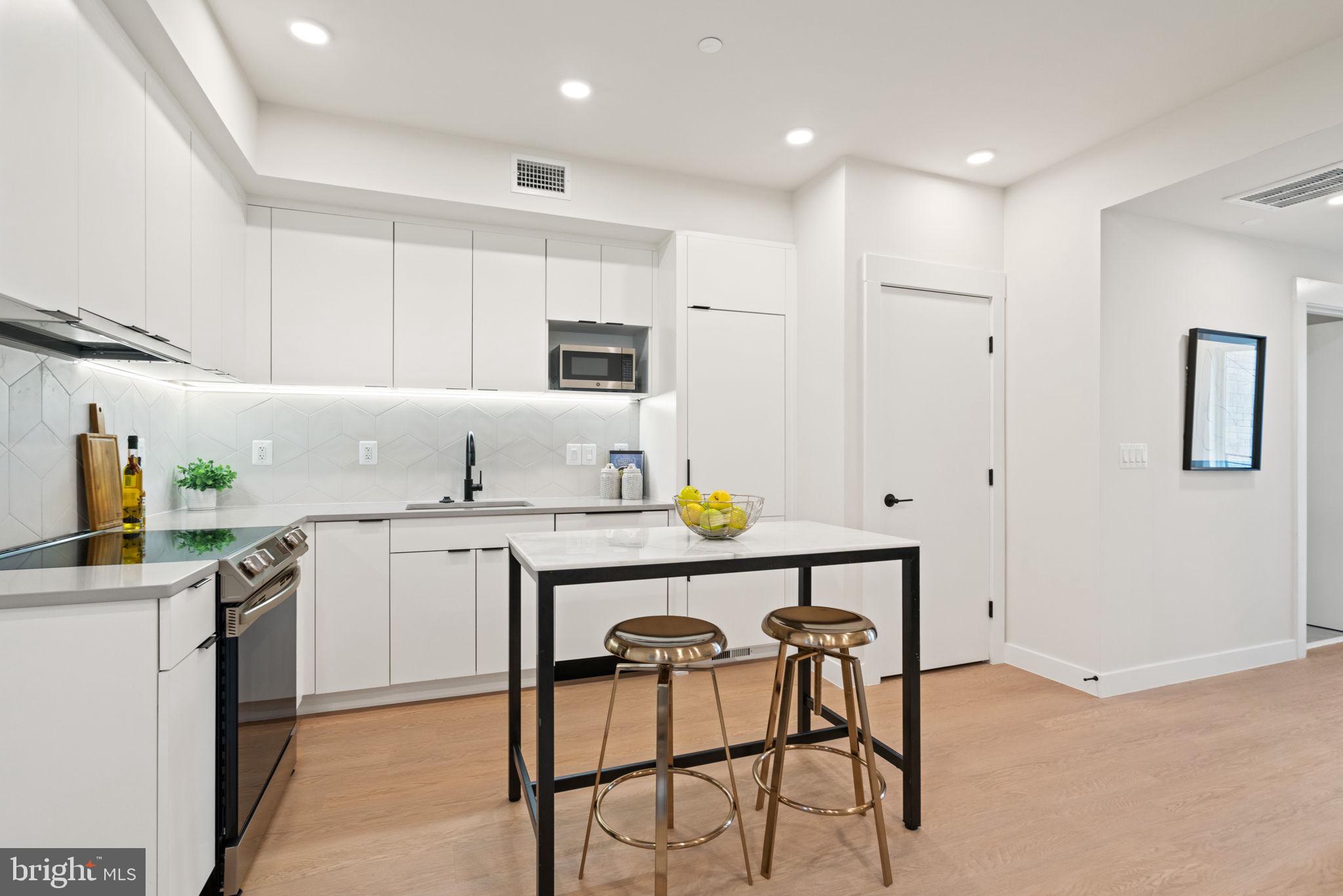 733 8th Street Southeast, Unit 1 Washington, DC 20003 - Photo 4 of 11 a kitchen with stainless steel appliances granite countertop a sink a stove a refrigerator a microwave with a dining table and chairs