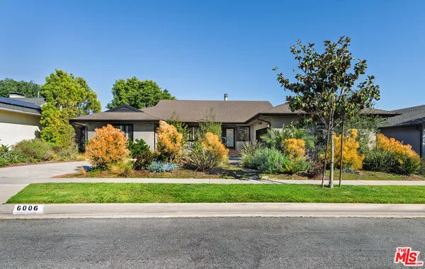 a front view of a house with a yard and potted plants