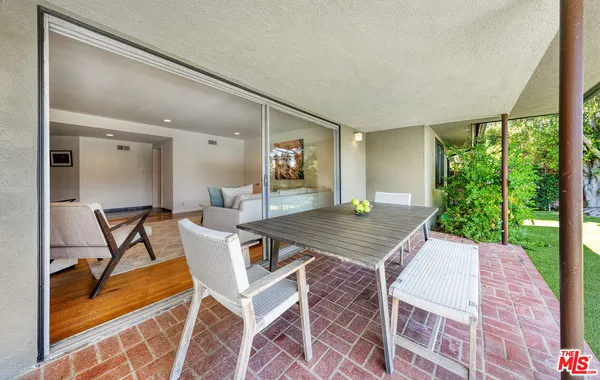 a view of a patio with table and chairs with wooden floor and fence