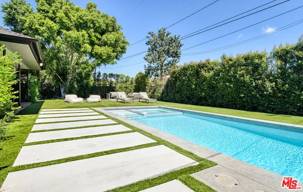 a view of swimming pool with lawn chairs and plants
