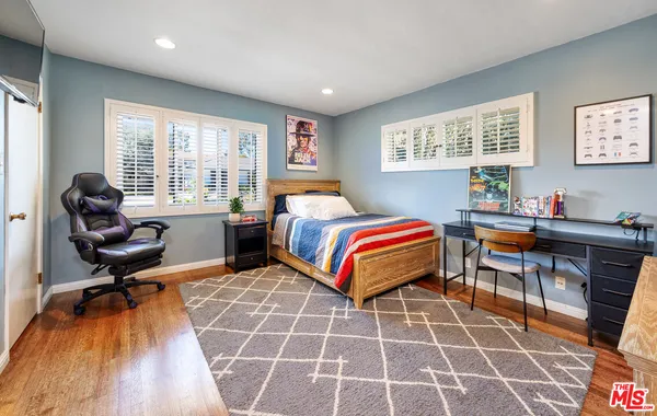 a bedroom with a bed and a flat tv screen on dresser