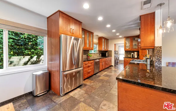 a large kitchen with granite countertop a stove a sink and a window