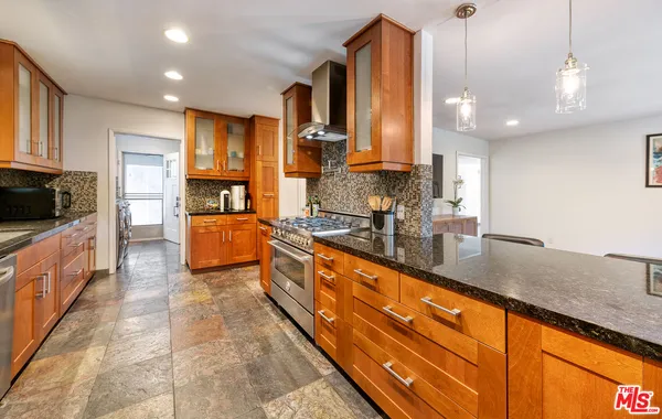 a large kitchen with stainless steel appliances granite countertop a lot of counter space and a window