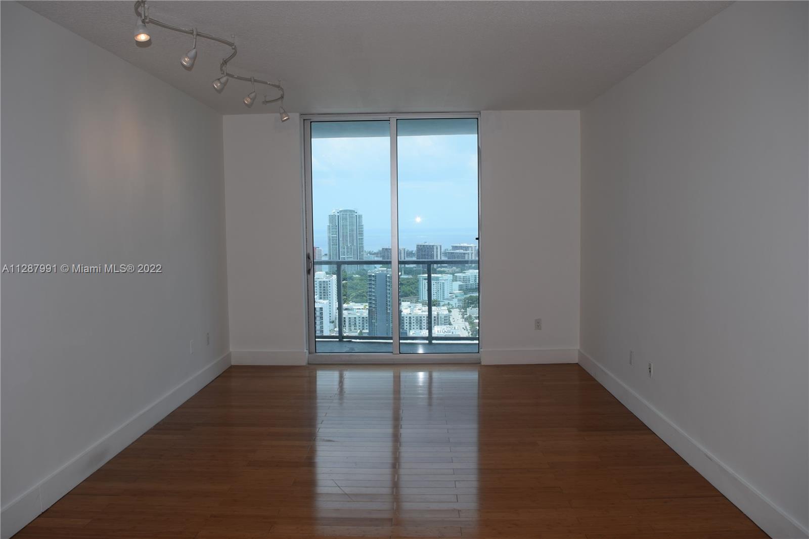 185 Southwest 7th Street, Unit 4014 Miami, FL 33130 - Photo 9 of 21 an empty room with wooden floor and windows
