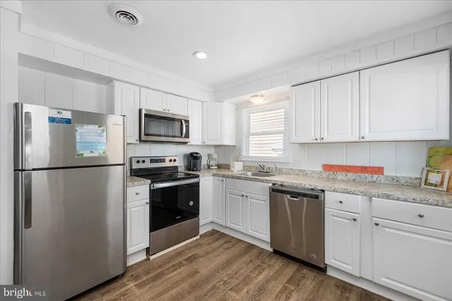 a kitchen with granite countertop white cabinets and stainless steel appliances