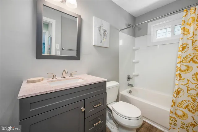 a bathroom with a granite countertop toilet a sink a mirror a shower curtain and a window