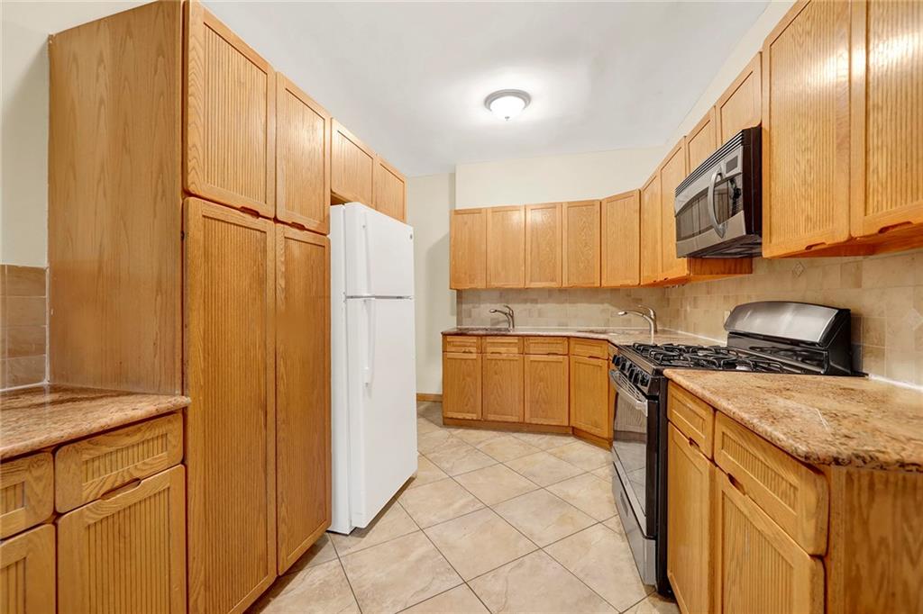 2602 Avenue T Brooklyn, NY 11229 - Photo 7 of 27 a kitchen with a refrigerator a stove top oven and cabinets